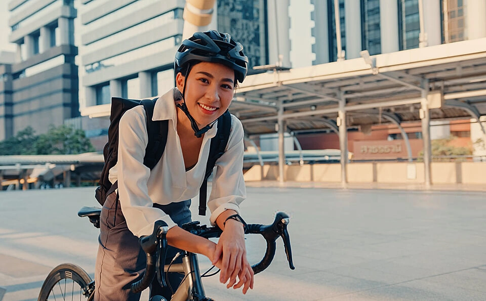 Businessfrau mit Helm und Rad lächelt in Kamera Businessfrau mit Helm und Rad lächelt in Kamera